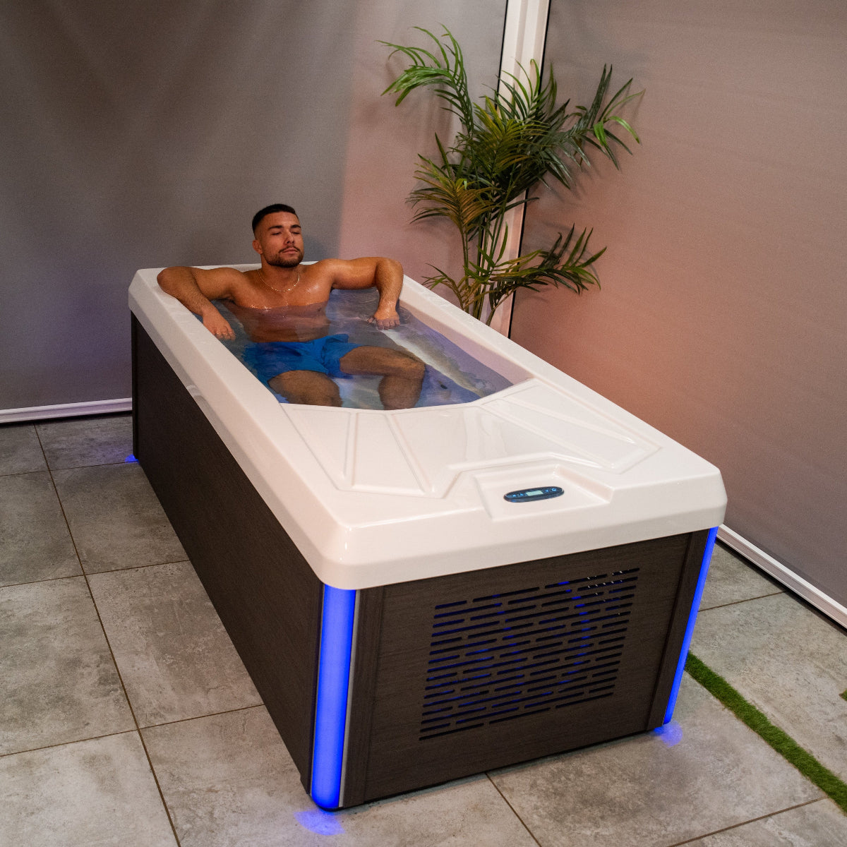 A man sitting in a compact ice bath in a tiled indoor room
