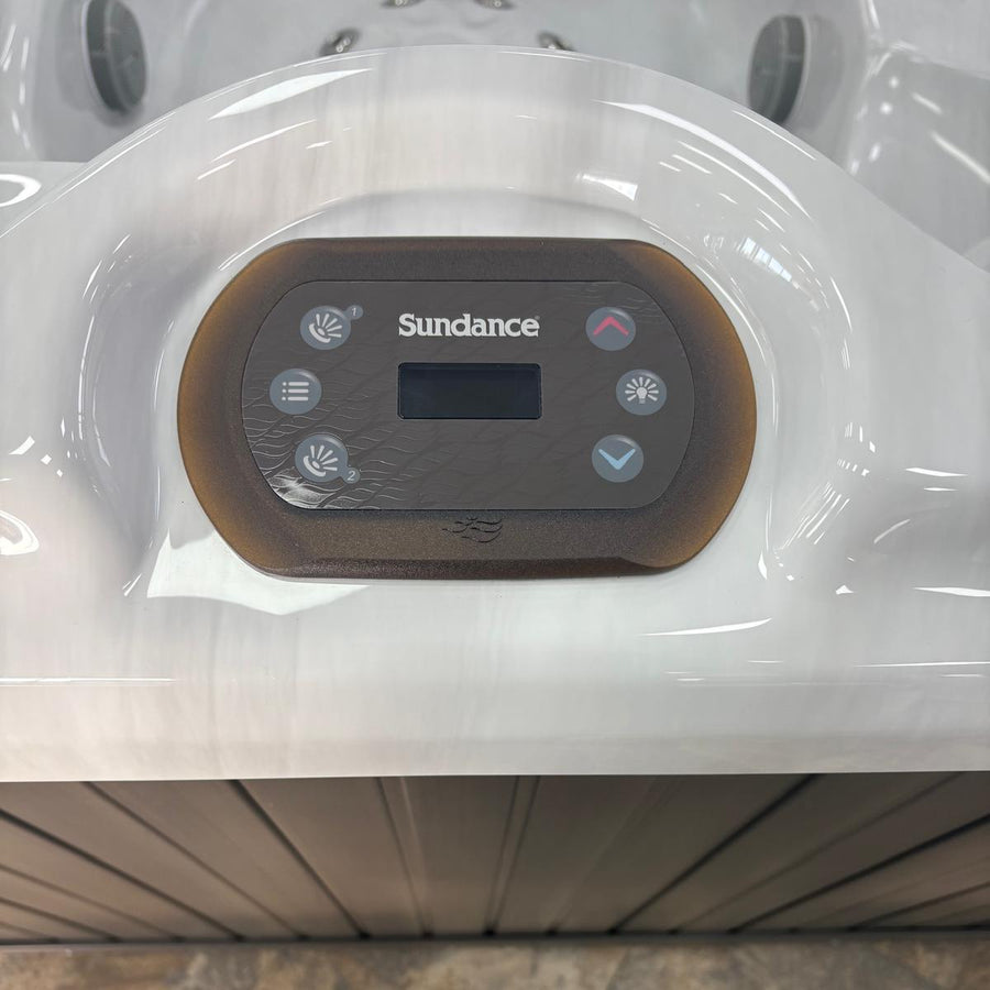 Control panel of a Sundance hot tub with a person's feet at the bottom.