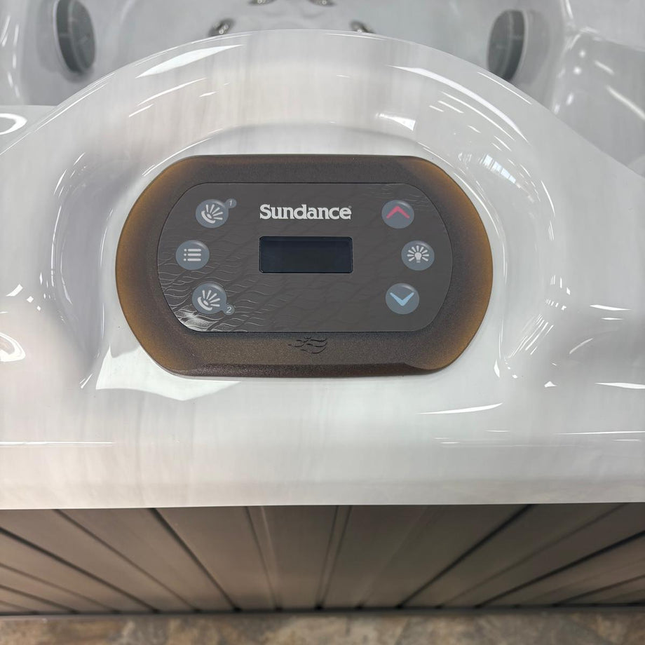 Control panel of a Sundance hot tub with a person's feet at the bottom.