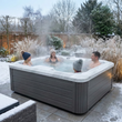 Load image into Gallery viewer, People enjoying a hot tub in a snowy garden setting
