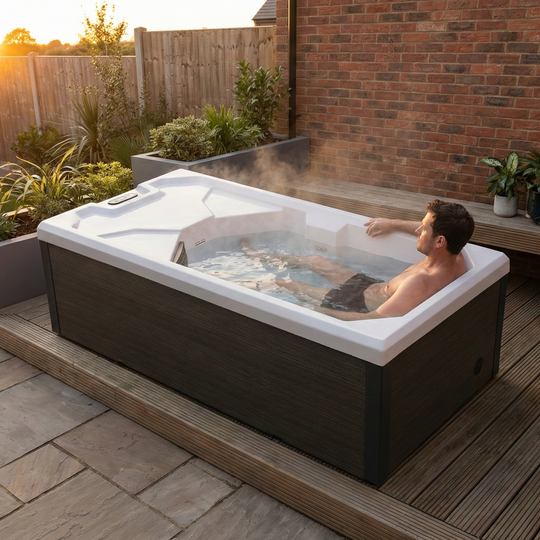 Man relaxing in a ice bath outdoors with sunset and garden in the background