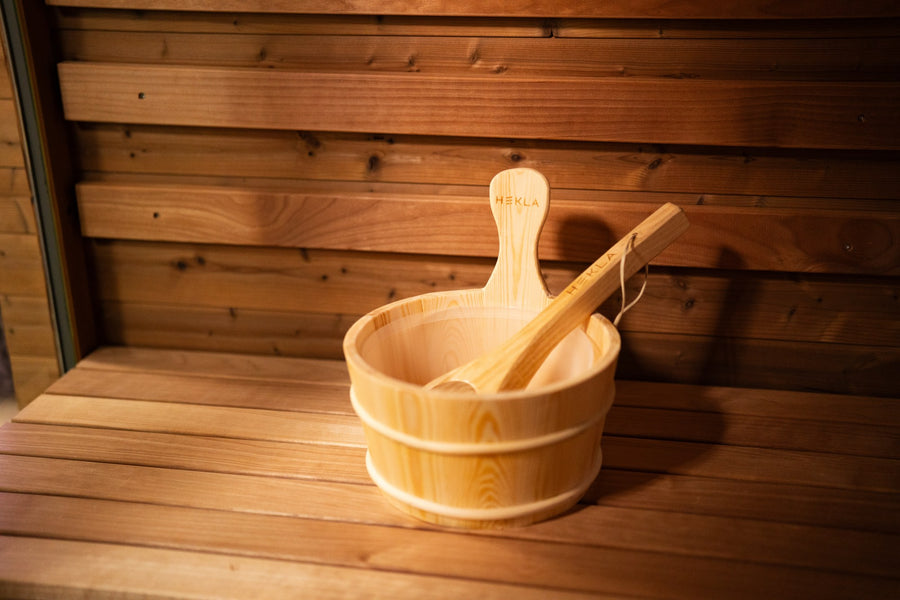 Hekla wooden sauna water bucket with a wooden ladle resting inside on a timber sauna bench
