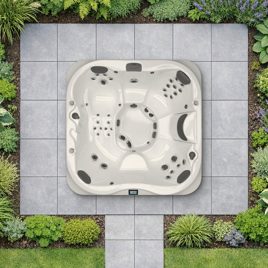 Jacuzzi J-335 hot tub shown at true scale from above in a planted garden (illustrative garden setting)
