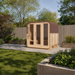 Load image into Gallery viewer, Illustrative lifestyle view of the Outdoor Living Cube sauna with its red-brown shingle roof in a UK garden
