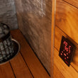 Load image into Gallery viewer, Black Harvia Cilindro heater beside a control panel in a timber sauna
