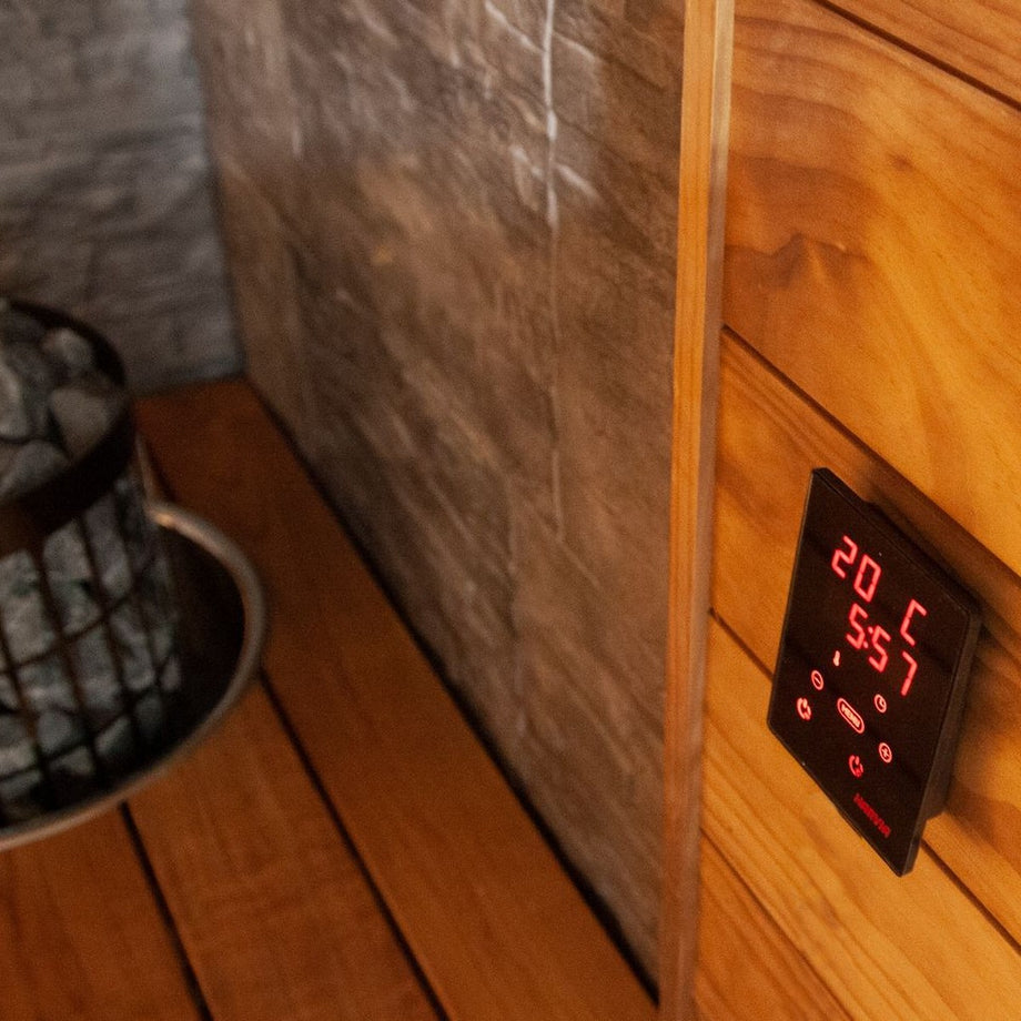 Black Harvia Cilindro heater beside a control panel in a timber sauna