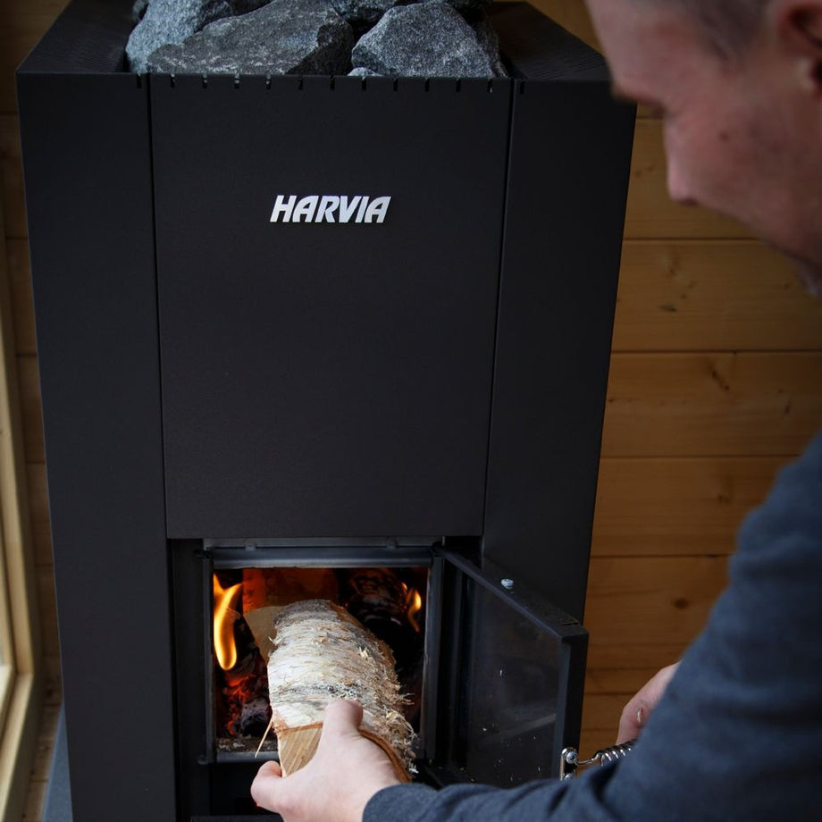 Loading wood into a Harvia Linear 18 Compact sauna stove
